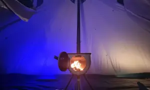 Piec w namiocie, płomienie tańczą w środku. Idealny sposób, jak ogrzać namiot zimową nocą.