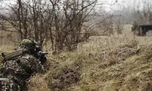 Gracz w kamuflażu leży w okopie, celując z repliki broni. Idealne miejsce, gdzie można strzelać z ASG, wśród zarośli i suchej trawy.