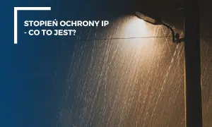 Lampa uliczna świeci w deszczu. Tekst: "Stopień ochrony IP - co to jest?". IP56 oznacza ochronę przed pyłem i silnymi strumieniami wody.