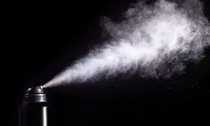 Chmura białego pyłu wydobywa się z czarnego aerozolu, ukazując potencjalne skutki gazu pieprzowego.