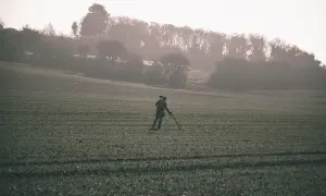Poszukiwacz skarbów z wykrywaczem metali na polu, szuka złota.