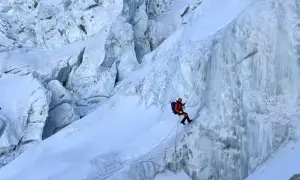 Wspinacz zjazdowy pokonuje lodospad na Everest. Lodowe formacje i śnieg tworzą niebezpieczną trasę.