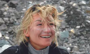 Martyna Wojciechowska z wiatrem we włosach, uśmiechnięta, na tle kamienistego zbocza. Może to być wspomnienie z wyprawy na Mount Everest.
