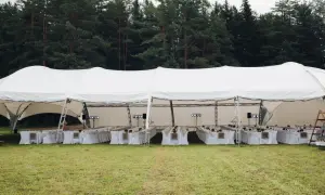 Duży biały namiot weselny z długimi stołami i krzesłami, gotowy na przyjęcie. Jak rozłożyć namiot? To proste, gdy masz taką konstrukcję!