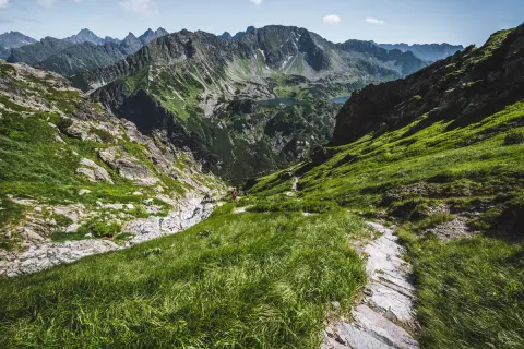 Malownicza dolina Pańszczycy w Tatrach, z zielonymi zboczami, kamienistym szlakiem i skalistymi szczytami w tle.