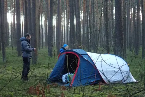Dwóch ludzi rozbija namiot w lesie. To ich przygoda z survivalem, co to znaczy? To nauka radzenia sobie w dziczy.