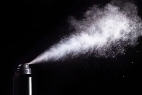 Chmura białego pyłu wydobywa się z czarnego aerozolu, ukazując potencjalne skutki gazu pieprzowego.
