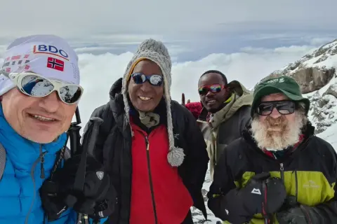 Czterech mężczyzn w górskim krajobrazie. Jeden z nich, w czapce z flagą Norwegii, przypomina o Aleksandrze Doba, którego śmierć wstrząsnęła światem.