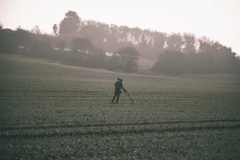 Poszukiwacz skarbów z wykrywaczem metali na polu, szuka złota.