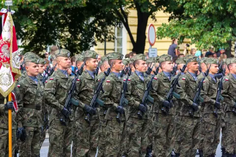 Żołnierze w mundurach polowych, z karabinami, maszerują w defiladzie. To widok z kategorii e wojsko, symbol dumy narodowej.