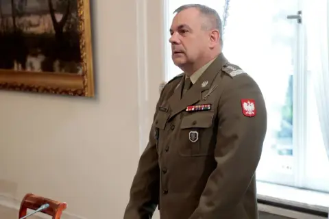 Generał w polskim mundurze, jeden z wielu na liście generałów w Polsce, stoi w sali.