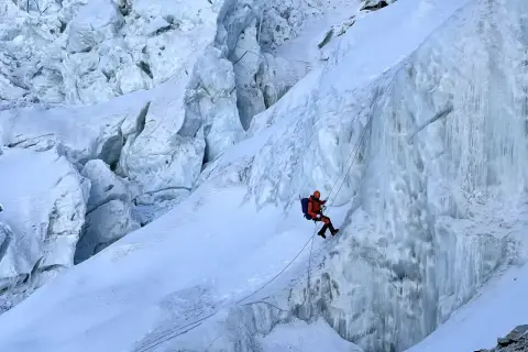 Wspinacz zjazdowy pokonuje lodospad na Everest. Lodowe formacje i śnieg tworzą niebezpieczną trasę.
