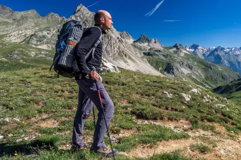 Mężczyzna z plecakiem wędruje przez malownicze tereny via alpina.