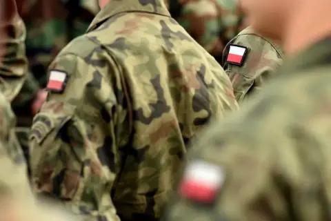 Żołnierze w mundurach moro z polskimi flagami na ramionach, symbolizujący chodzenie w mundurze poza jednostką.