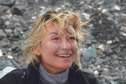 Martyna Wojciechowska z wiatrem we włosach, uśmiechnięta, na tle kamienistego zbocza. Może to być wspomnienie z wyprawy na Mount Everest.