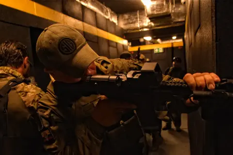 Żołnierze ćwiczą taktykę CQB (Close Quarters Battle) w ciasnych korytarzach, przygotowując się do walki na bliskim dystansie.