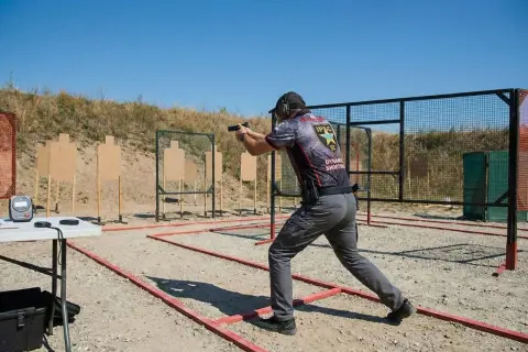 Strzelec w dynamicznej postawie na strzelnicy IPSC. To właśnie ipsc co to jest – sportowe strzelanie dynamiczne.