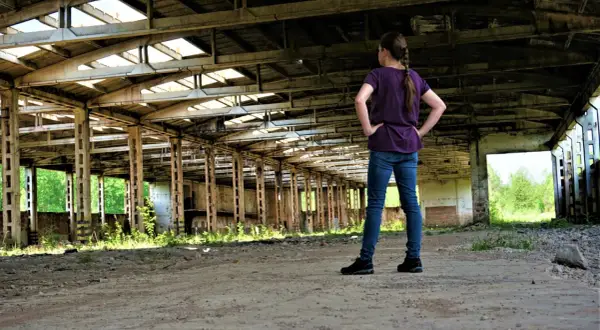Dziewczyna w zrujnowanej hali, zastanawia się, czy urbex jest legalny.