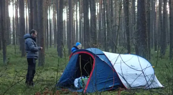 Dwóch ludzi rozbija namiot w lesie. To ich przygoda z survivalem, co to znaczy? To nauka radzenia sobie w dziczy.