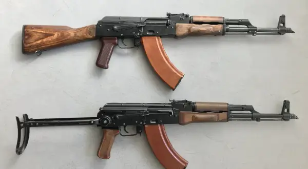 Dwa karabiny AK-47 z drewnianymi i brązowymi elementami. Standardowy magazynek mieści 30 naboi, ale istnieją też większe.