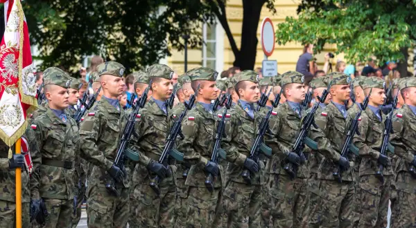 Żołnierze w mundurach polowych, z karabinami, maszerują w defiladzie. To widok z kategorii e wojsko, symbol dumy narodowej.
