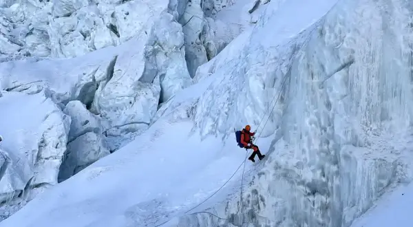 Wspinacz zjazdowy pokonuje lodospad na Everest. Lodowe formacje i śnieg tworzą niebezpieczną trasę.