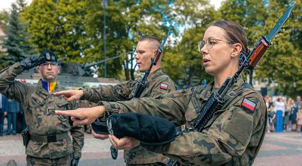 Żołnierze w mundurach polowych, z karabinami, przygotowują się do przysięgi wojskowej. To ważny moment, jak się ubrać na przysięgę wojskową? Mundur to podstawa.