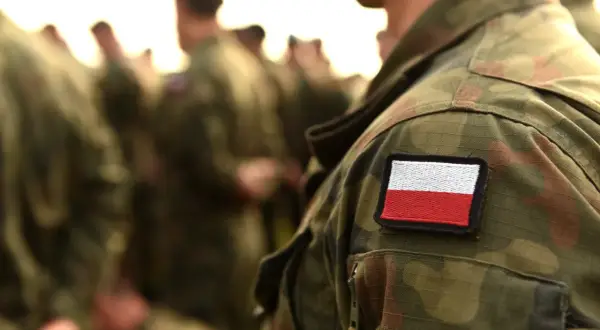 Żołnierz w mundurze z polską flagą. Czy warto iść do wojska? To pytanie, na które każdy musi odpowiedzieć sam.