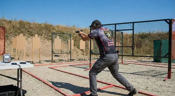 Strzelec w dynamicznej postawie na strzelnicy IPSC. To właśnie ipsc co to jest – sportowe strzelanie dynamiczne.