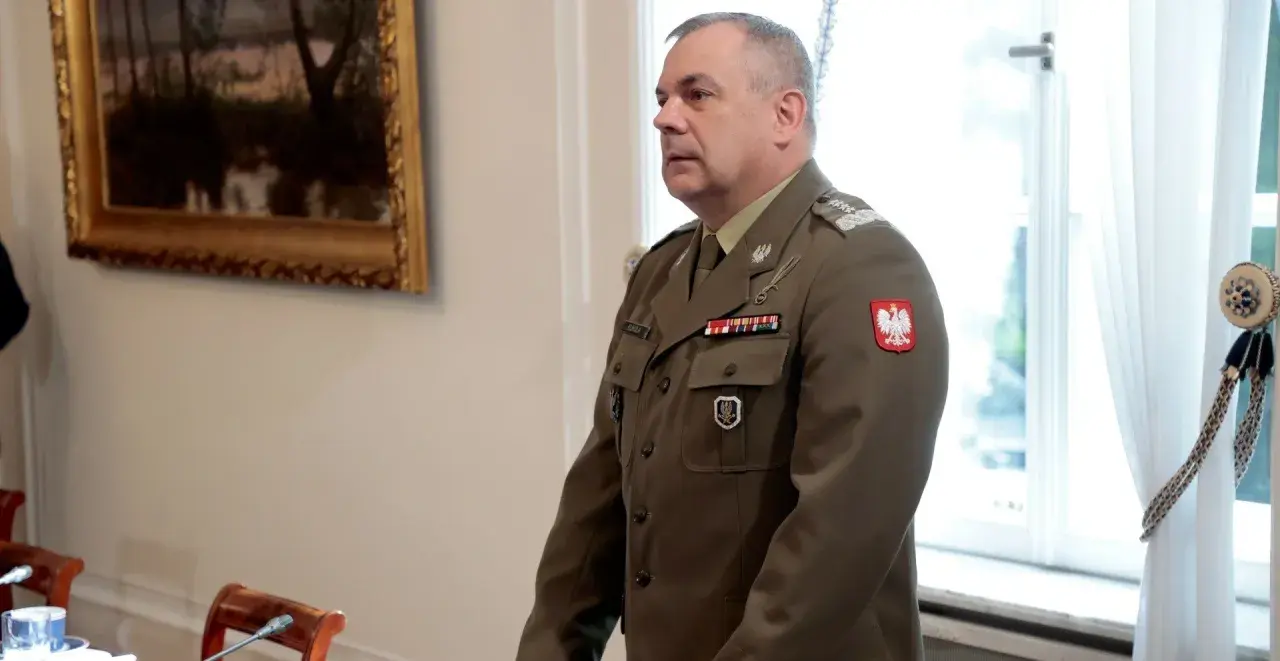 Generał w polskim mundurze, jeden z wielu na liście generałów w Polsce, stoi w sali.