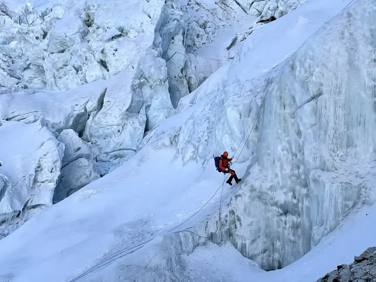 Wspinacz zjazdowy pokonuje lodospad na Everest. Lodowe formacje i śnieg tworzą niebezpieczną trasę.