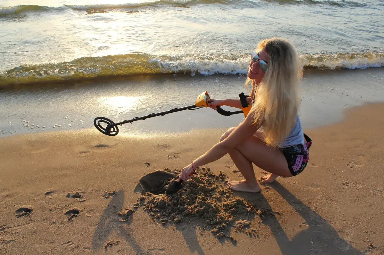Dziewczyna z wykrywaczem na plaży szuka skarbów. Czy można chodzić z wykrywaczem po plaży? Tak, jeśli nie narusza to przepisów!