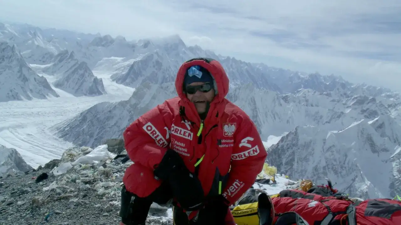 Wspinacz na szczycie Broad Peak podczas wyprawy na Broad Peak 2013. W tle majestatyczne, ośnieżone góry.