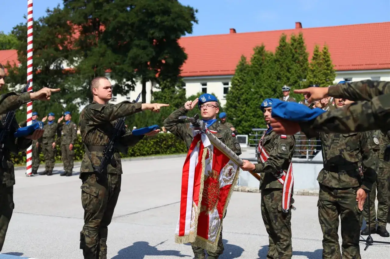 Żołnierze w mundurach polowych, niebieskich beretach i z biało-czerwoną flagą. Warto wiedzieć, jak się ubrać na przysięgę wojskową, by wyglądać godnie.