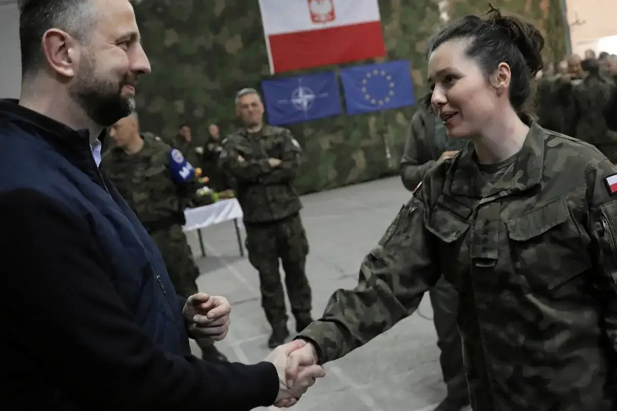 Kobieta w mundurze wojskowym uśmiecha się, ściskając dłoń. To inspiracja dla kobiet, jak dostać się do wojska.