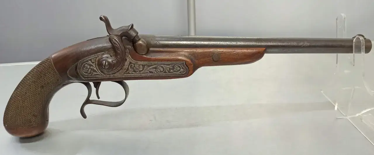 Stary pistolet, broń czarnoprochowa, z drewnianą rękojeścią i metalowymi zdobieniami.