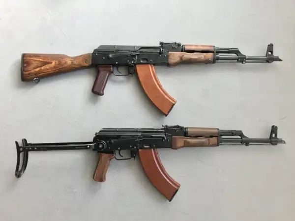 Dwa karabiny AK-47 z drewnianymi i brązowymi elementami. Standardowy magazynek mieści 30 naboi, ale istnieją też większe.
