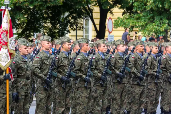 Żołnierze w mundurach polowych, z karabinami, maszerują w defiladzie. To widok z kategorii e wojsko, symbol dumy narodowej.
