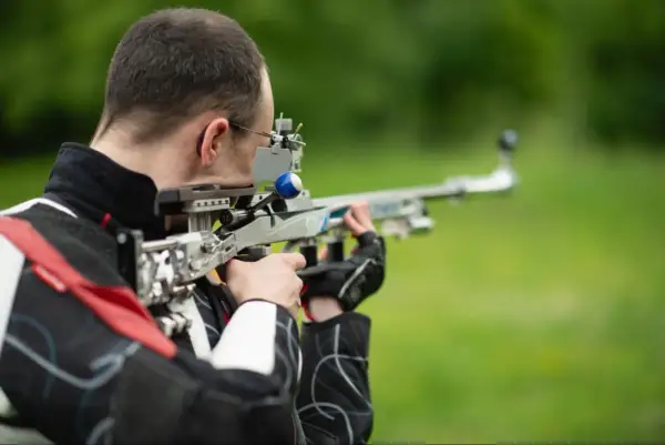 Strzelec celuje z wiatrówki sportowej. Zastanawiasz się, jaki zasięg ma wiatrówka? Ten model pozwala na precyzyjne strzelanie na znaczne odległości.