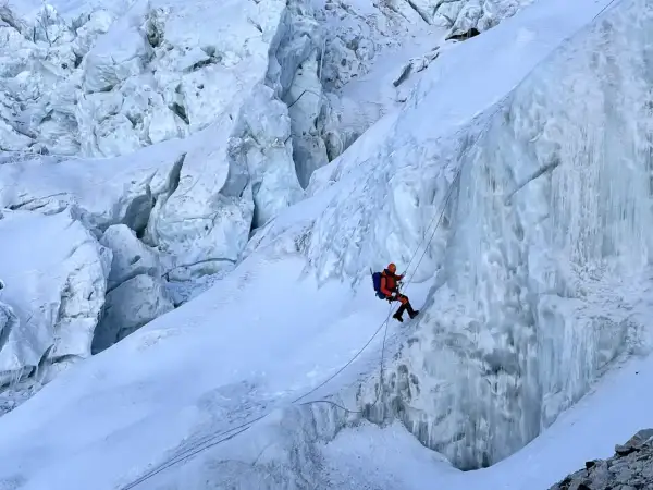 Wspinacz zjazdowy pokonuje lodospad na Everest. Lodowe formacje i śnieg tworzą niebezpieczną trasę.